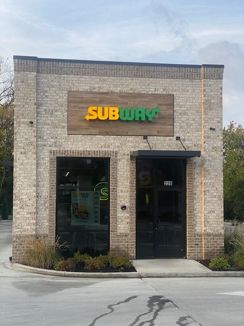 Exterior of a Subway restaurant in a brick building with a sign above the door.