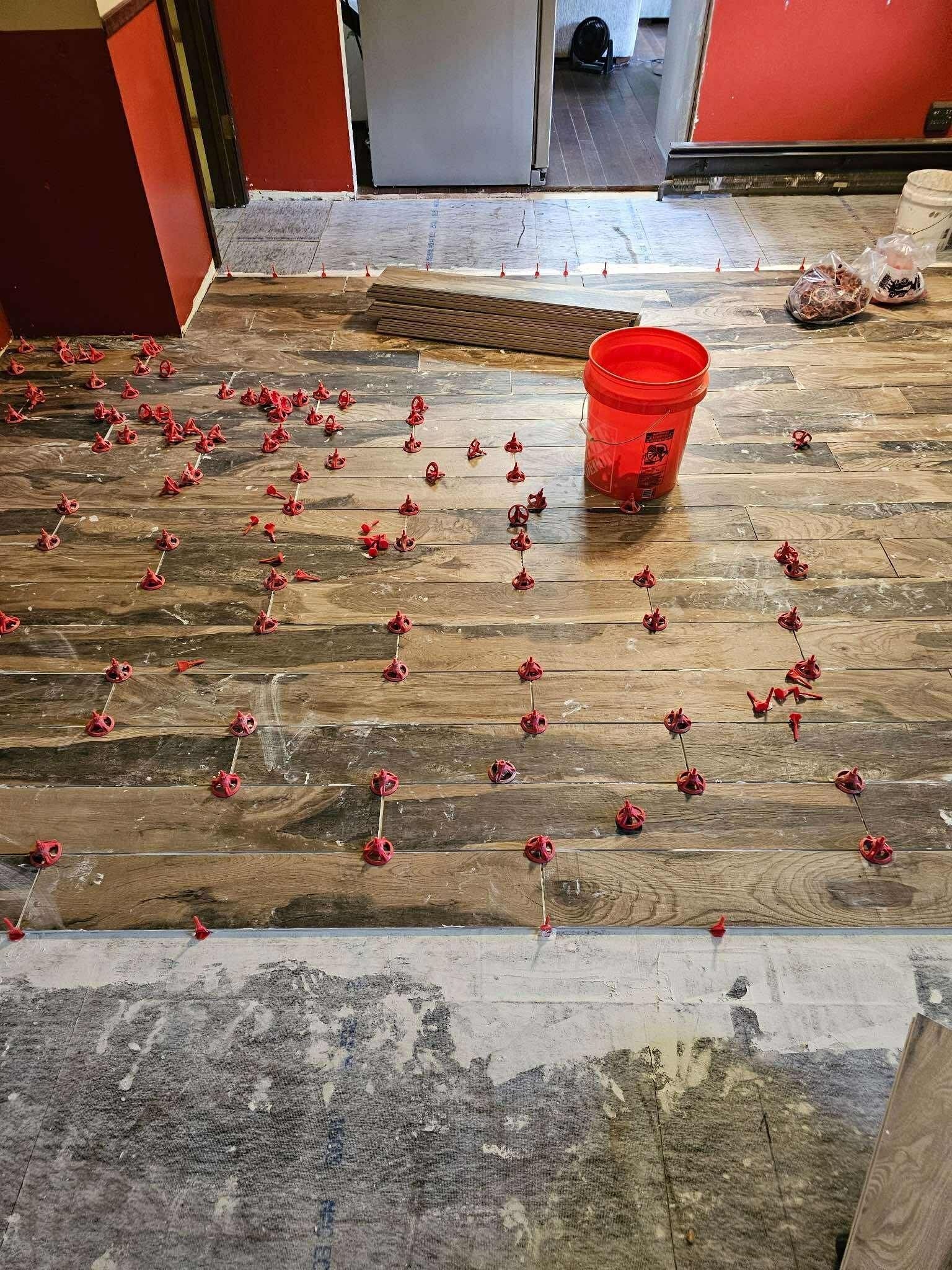 Red bucket on a wooden porch scattered with red flower petals near a doorway