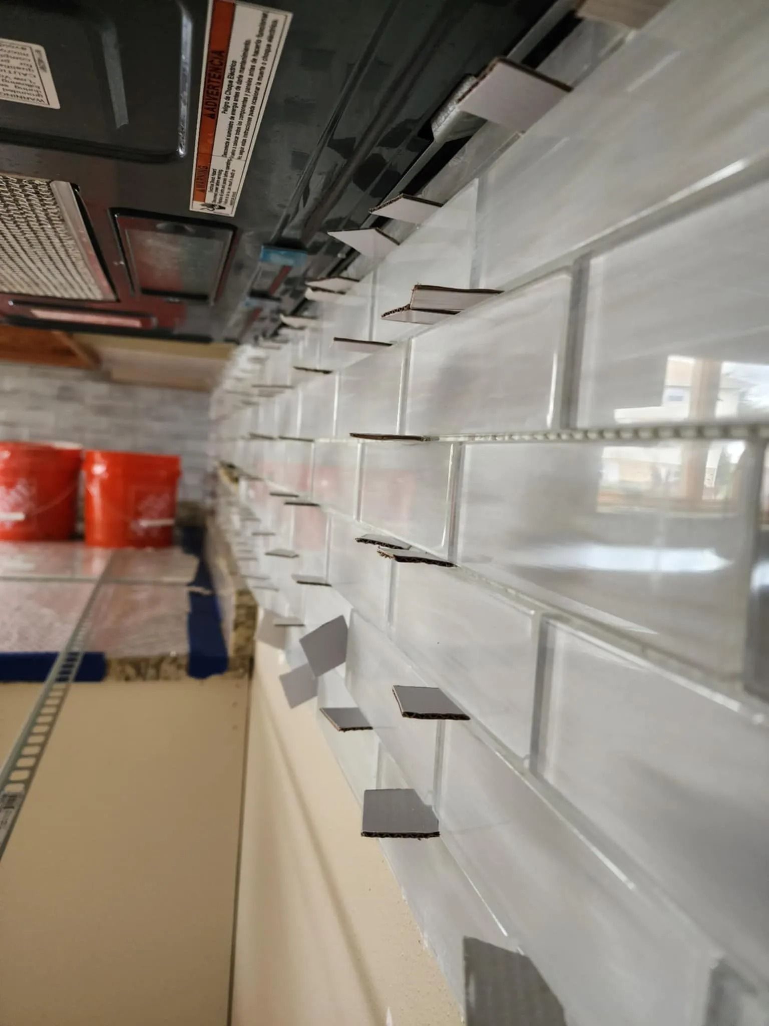 Store aisle with empty white shelves and red buckets in the background, viewed at an angle.