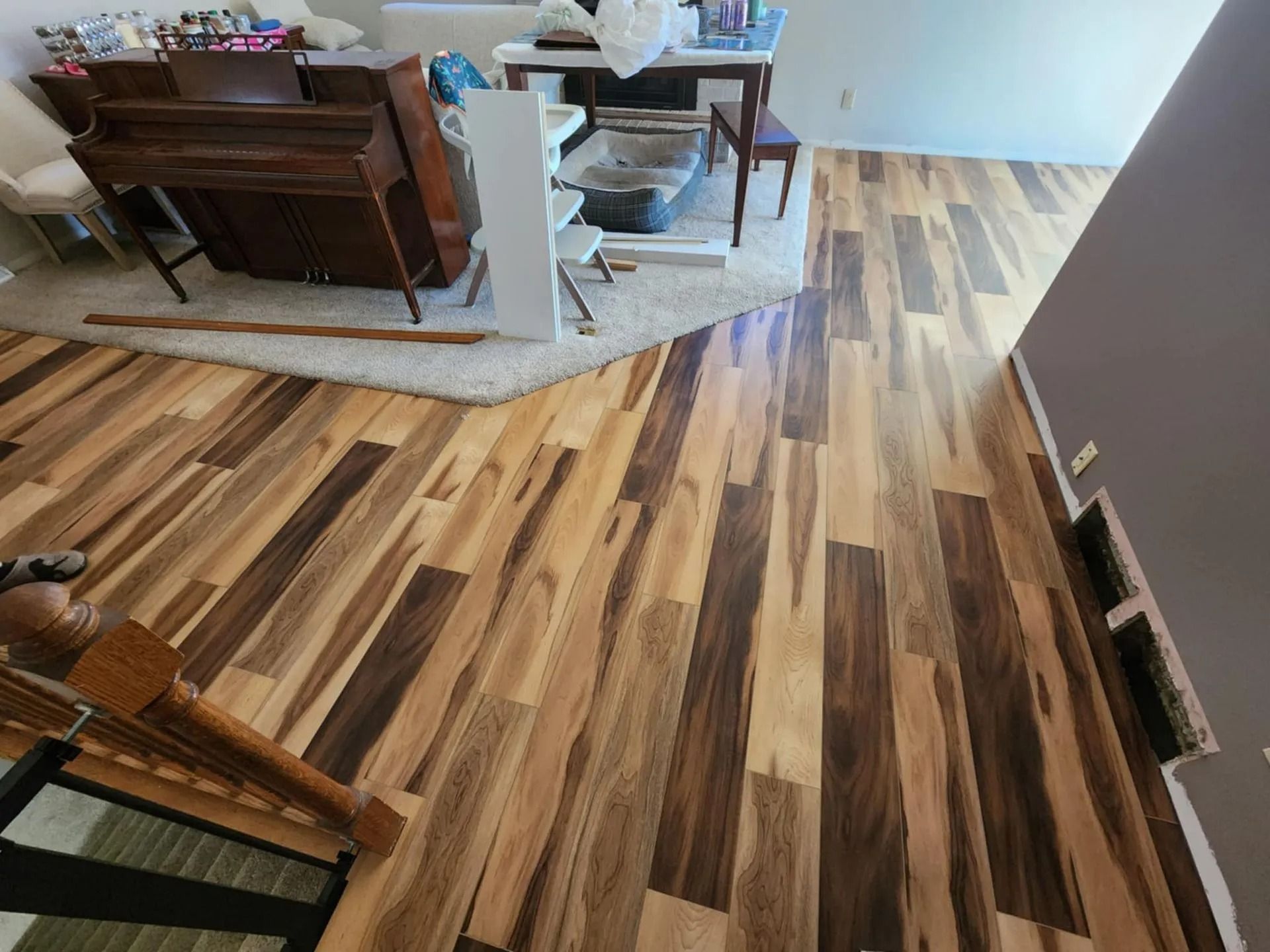 Dining room with wood-look flooring, dark table and chairs, and a white baby gate near the wall.