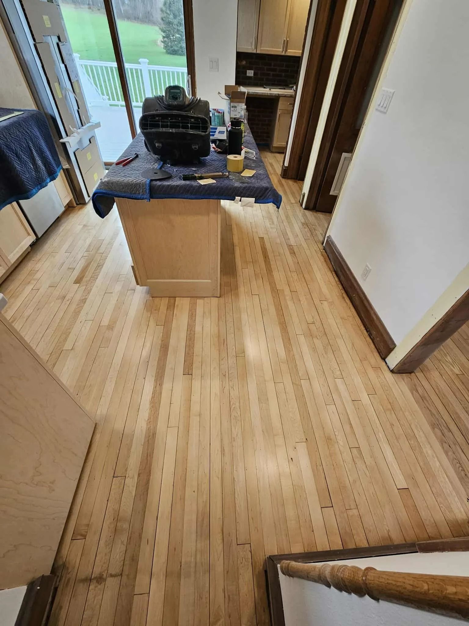 Narrow home hallway with light wood floors and a central table near a window and fireplace.