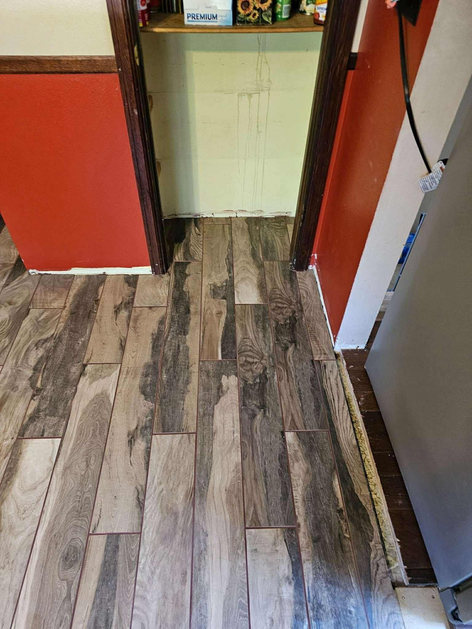 Narrow hallway with wood-look tile floor, red walls, and a small tiled alcove at the end.