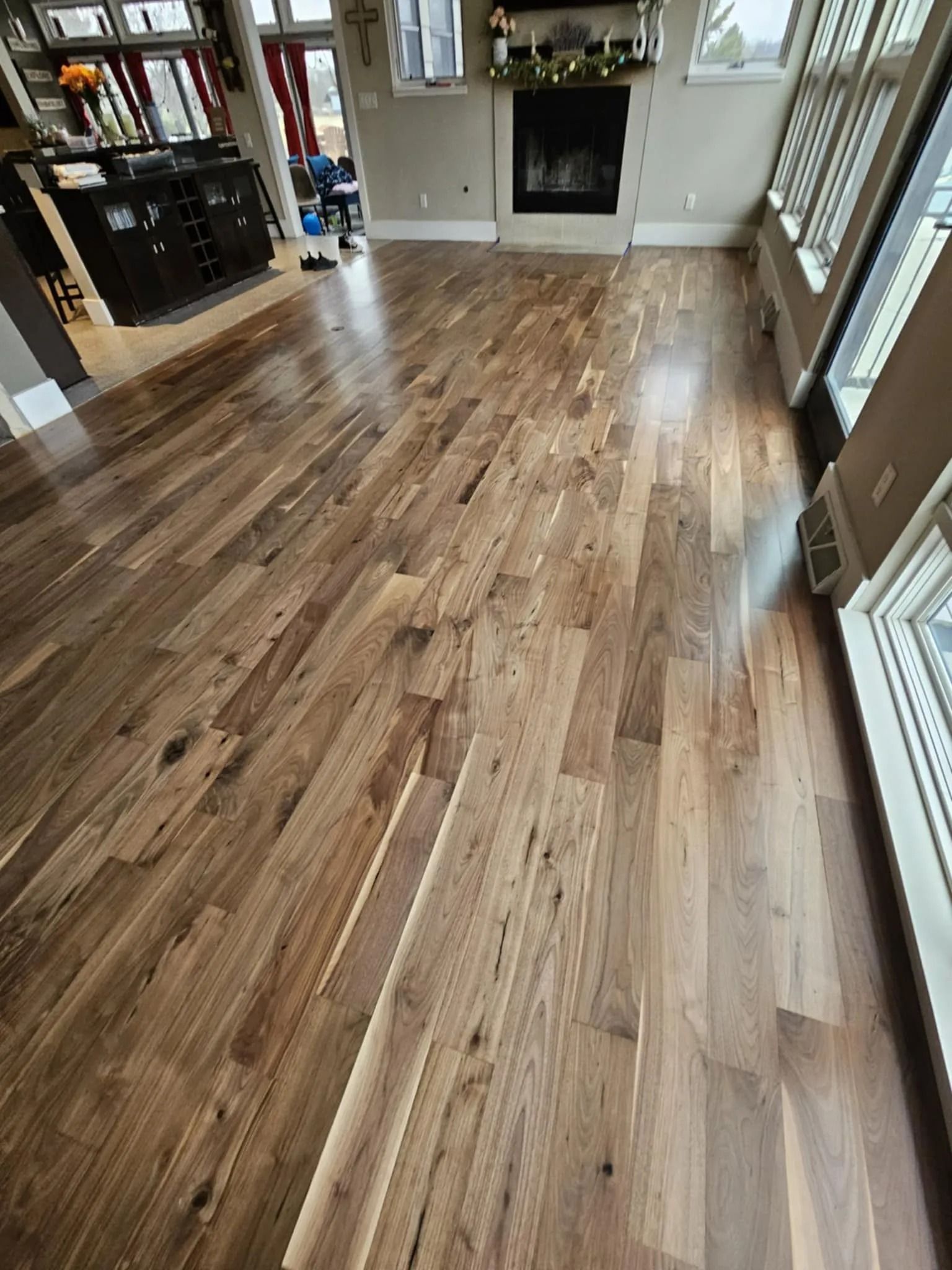 Polished hardwood floor in a bright room with a fireplace and large windows
