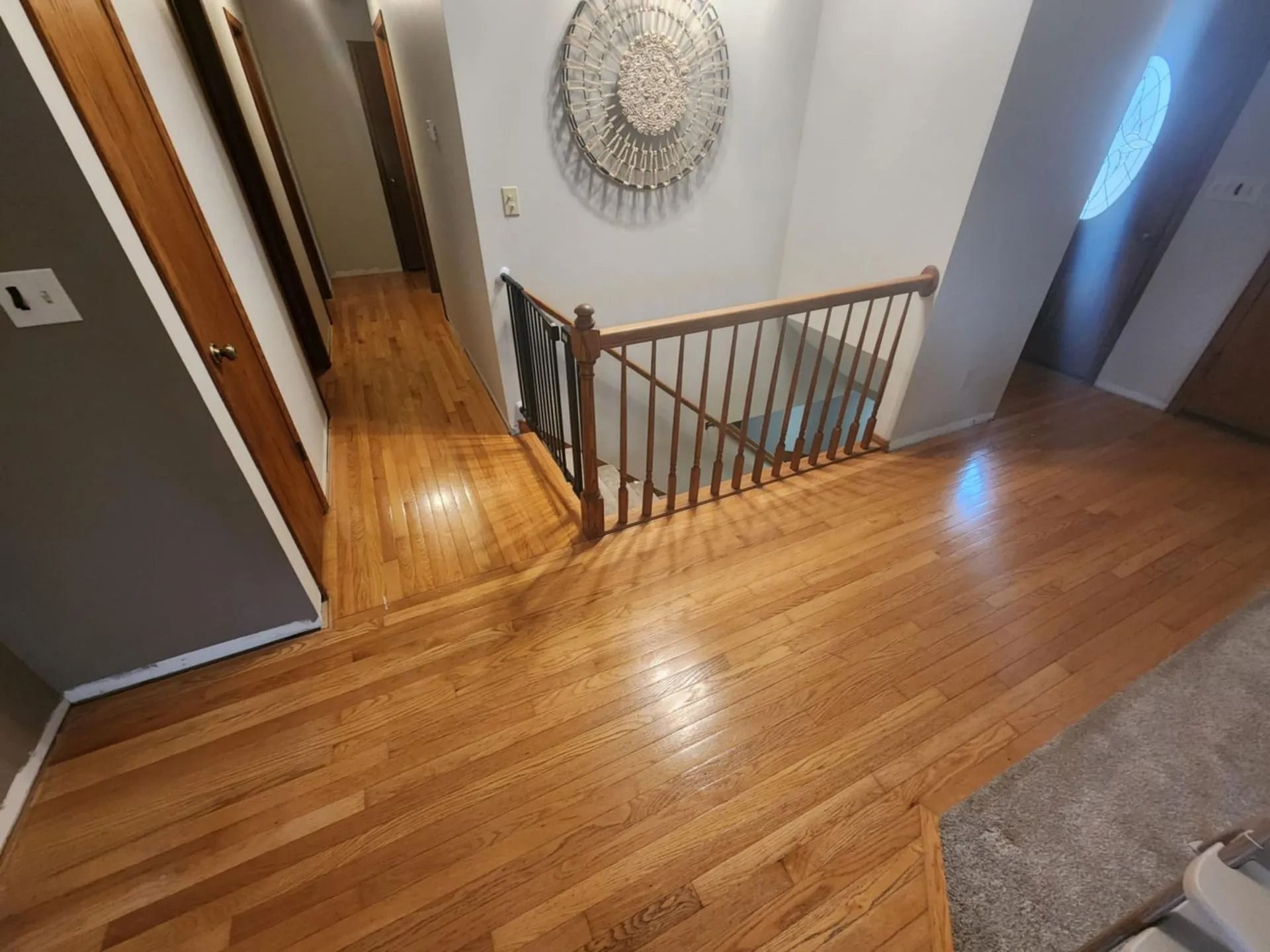 Stair landing with wooden floors, railing, and hallway doors in a home interior