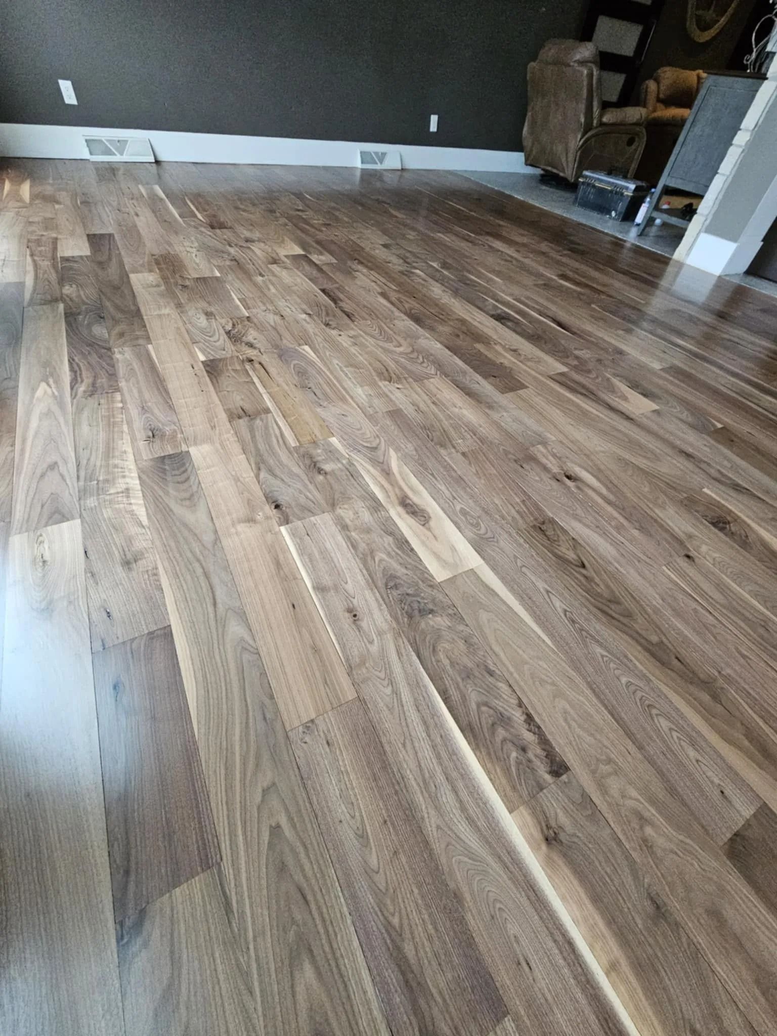 Empty room with light wood plank flooring and a white wall, viewed from a low angle
