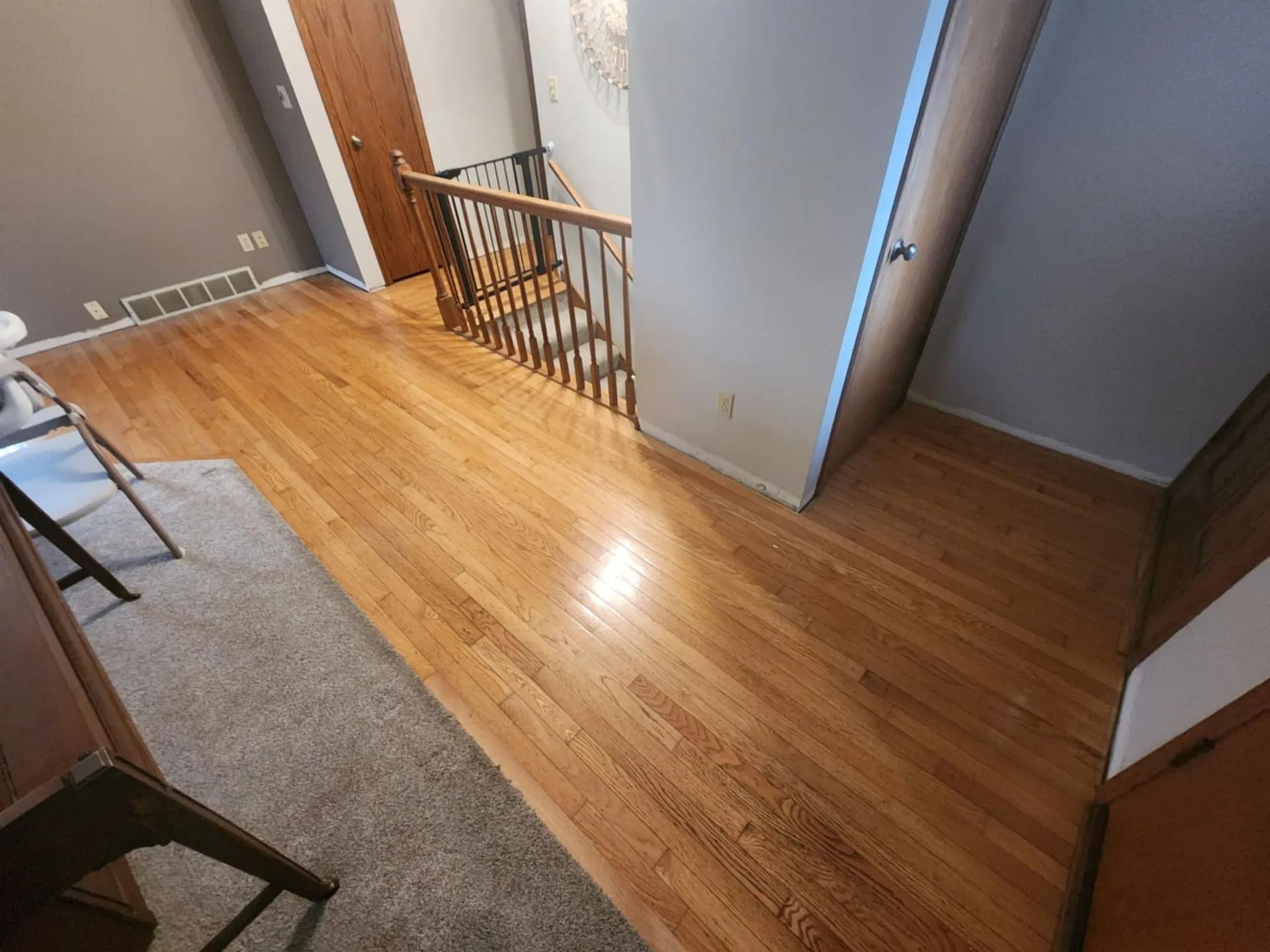 Wooden upstairs hallway with railing and open doors, viewed from above