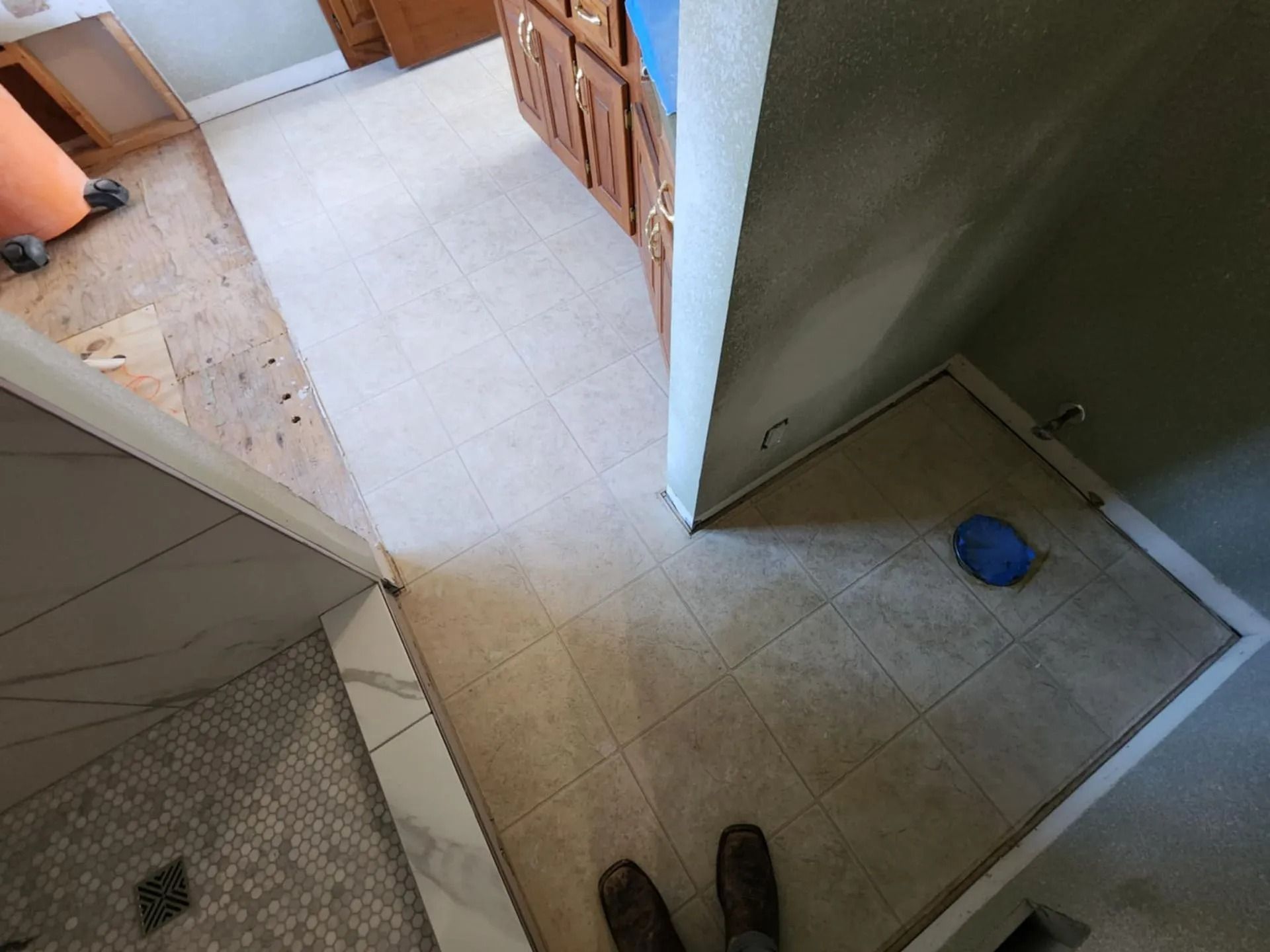 Top-down view of a tiled hallway and adjacent rooms, with a pair of shoes at the bottom and a blue bowl on the floor.