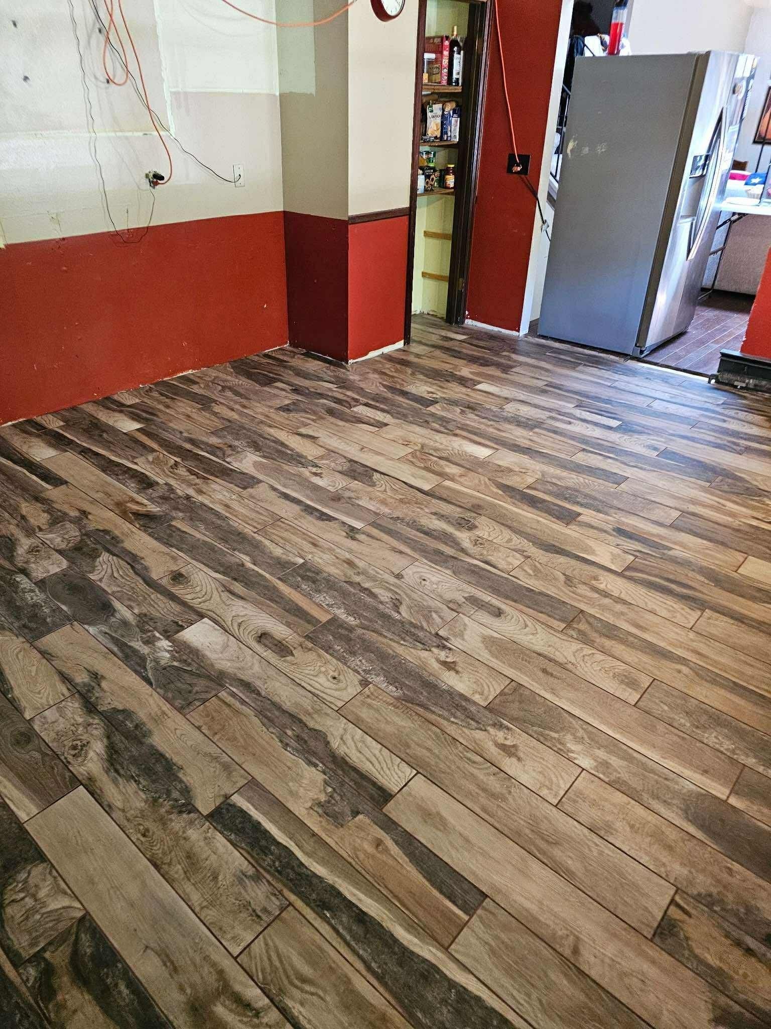 Empty room with wood-look floor, red lower walls, and an open doorway to a kitchen area.