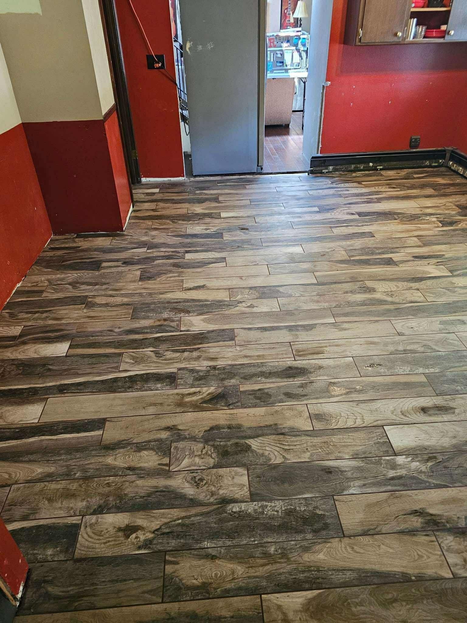 Empty hallway with wood-look flooring, red walls, and an open door at the far end.