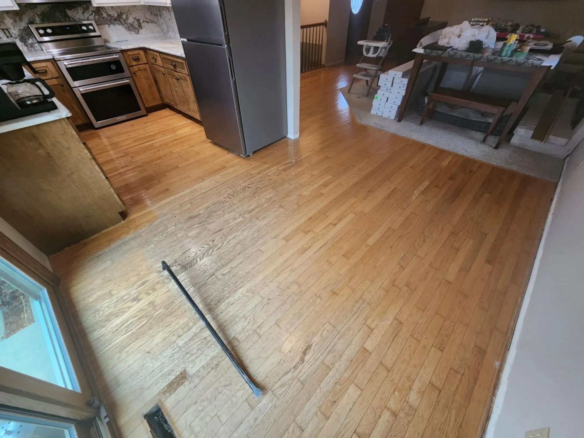 Open kitchen with hardwood floors, stainless steel appliances, and dining table in the background.