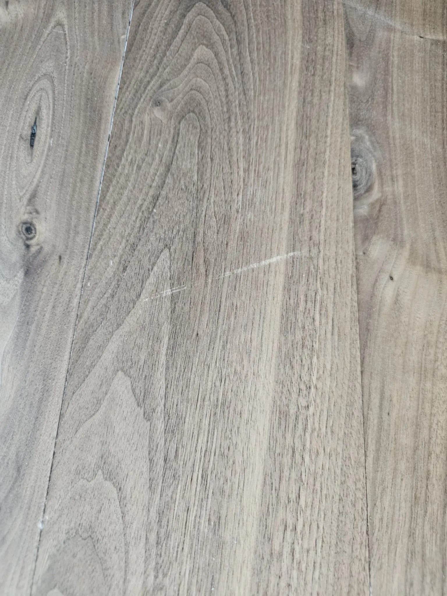 Gray wood grain texture with subtle wavy patterns and knots