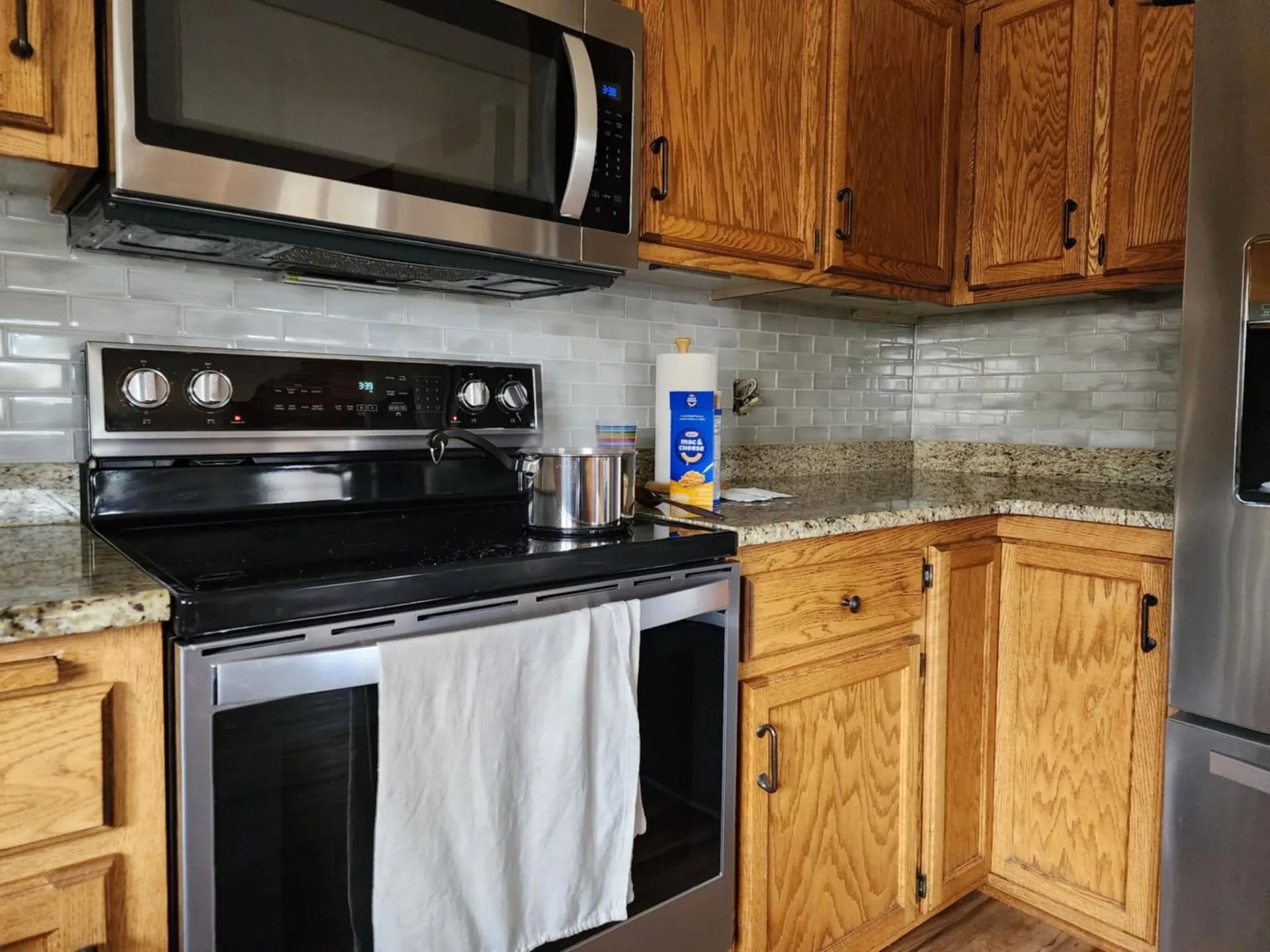 Modern kitchen with black stove, stainless microwave, wood cabinets, and granite countertops