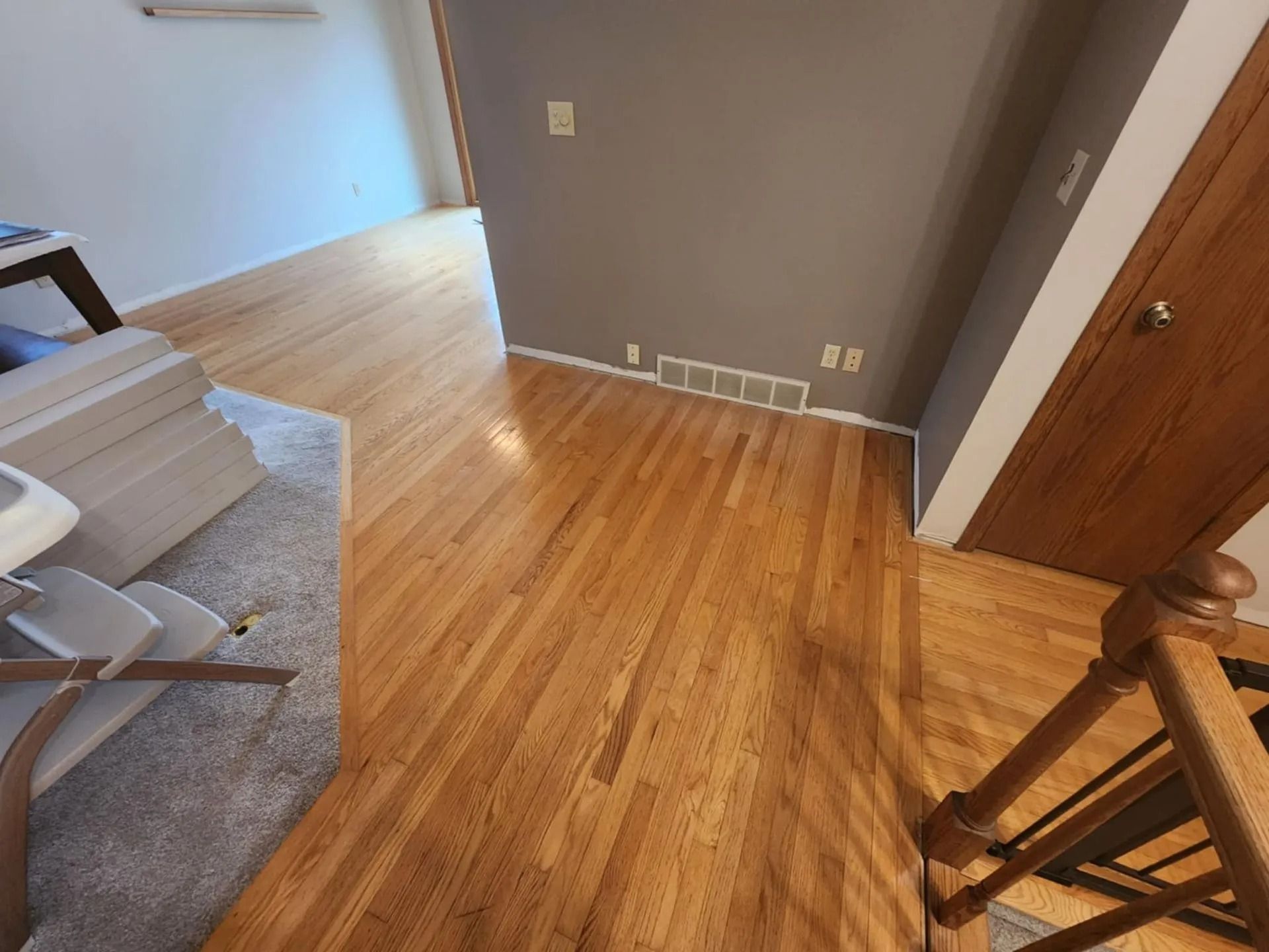 Empty living room with hardwood floor, gray walls, and a doorway on the right.