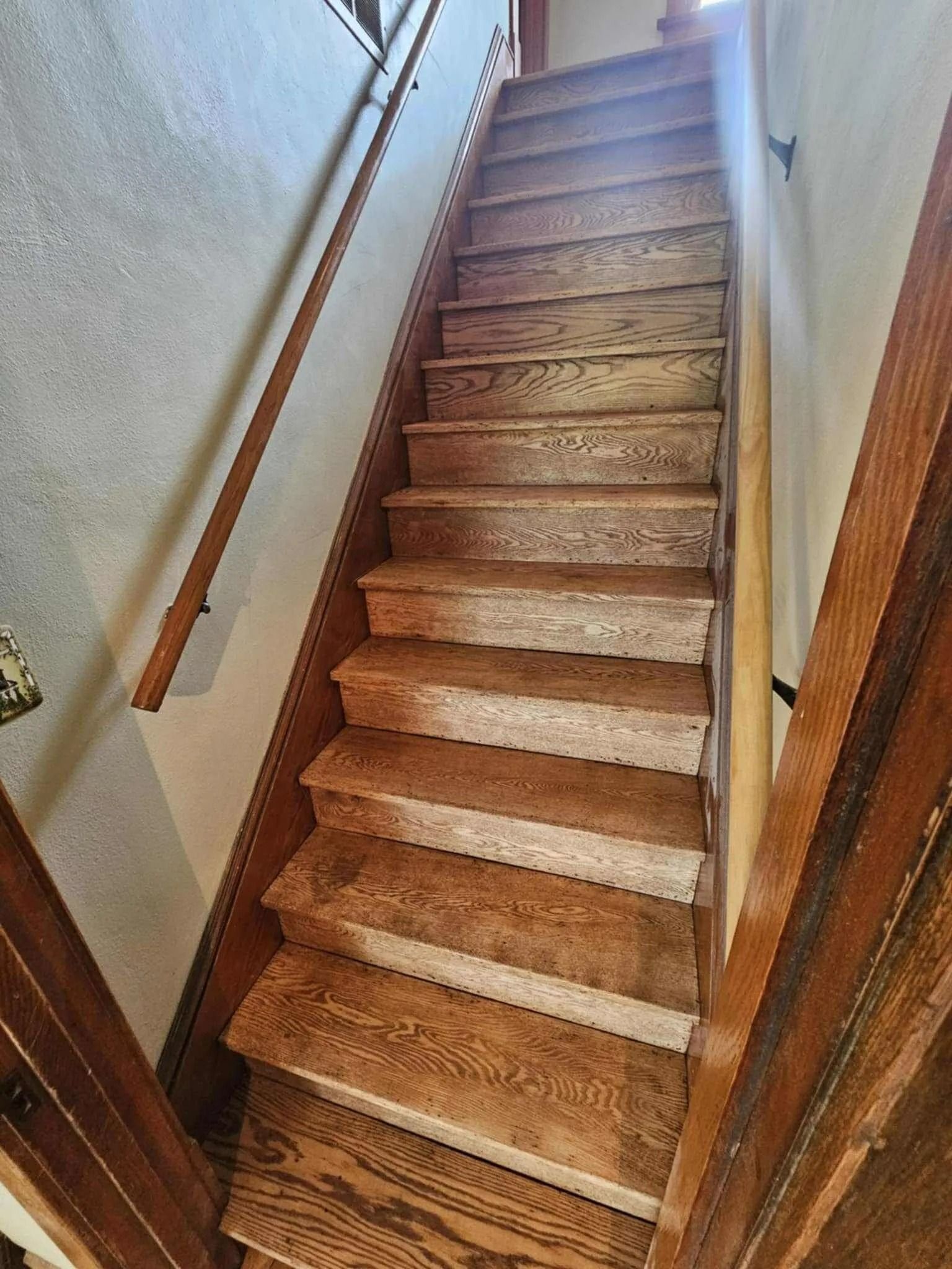 Narrow carpeted staircase with wooden handrails in a house interior
