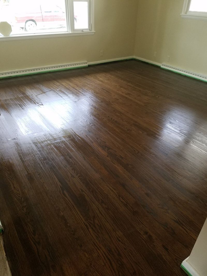 Empty room with glossy dark hardwood floors and a window letting in daylight