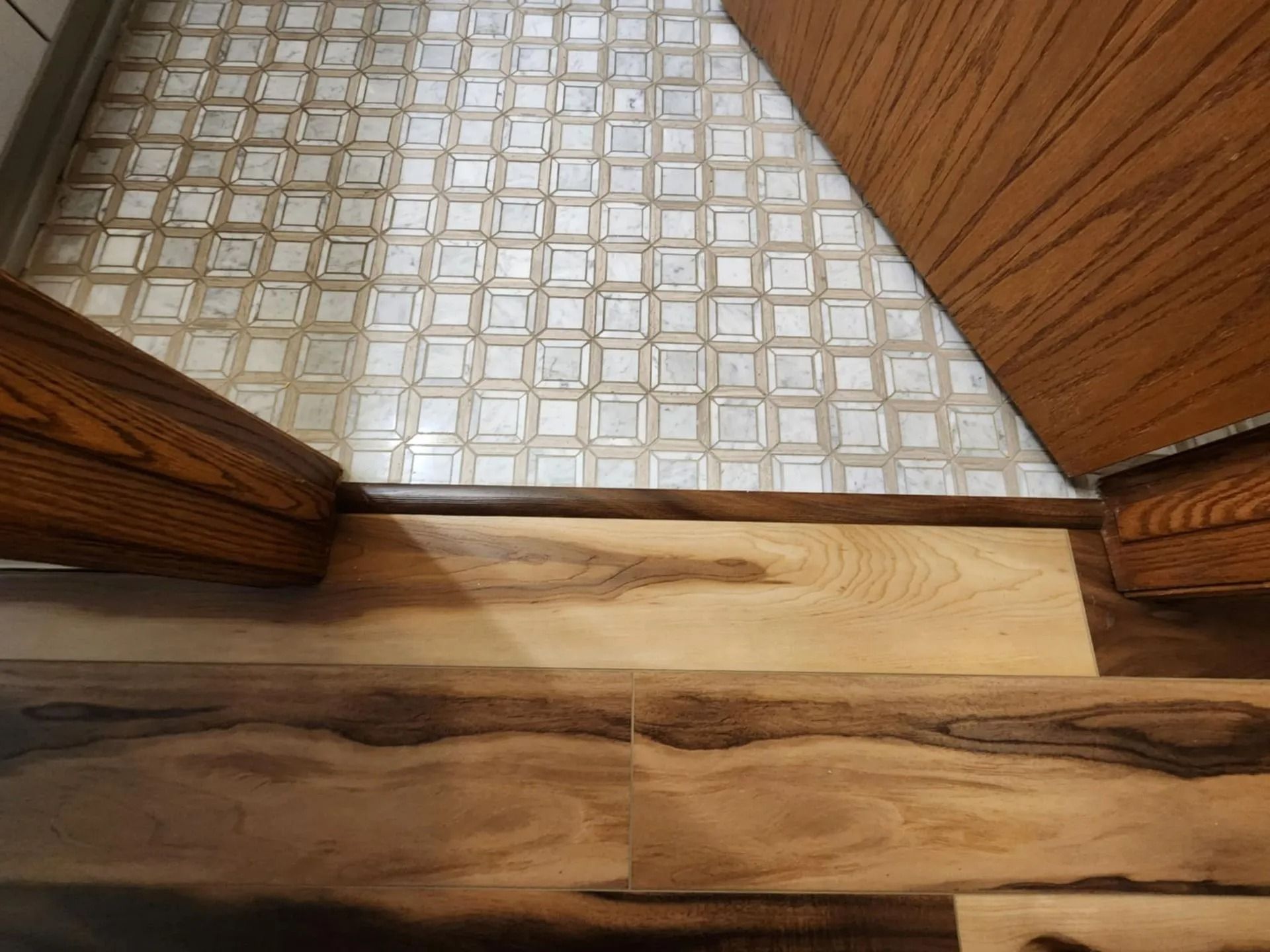 Wood-and-tile floor transition between two rooms with wooden door frames, viewed from above