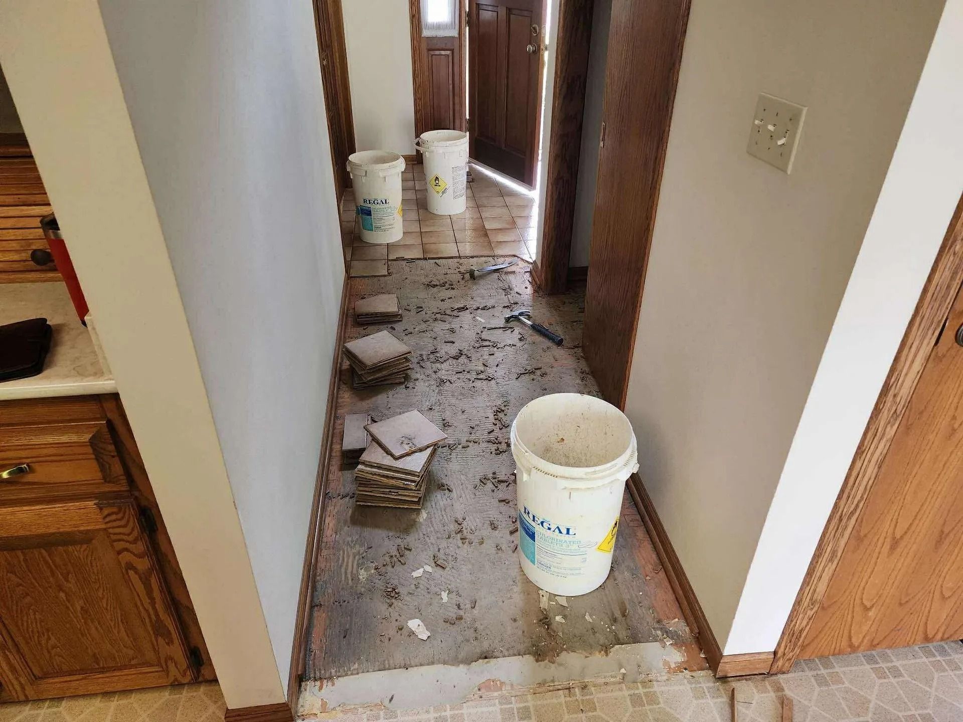Hallway under renovation with debris on the floor and white buckets of construction materials