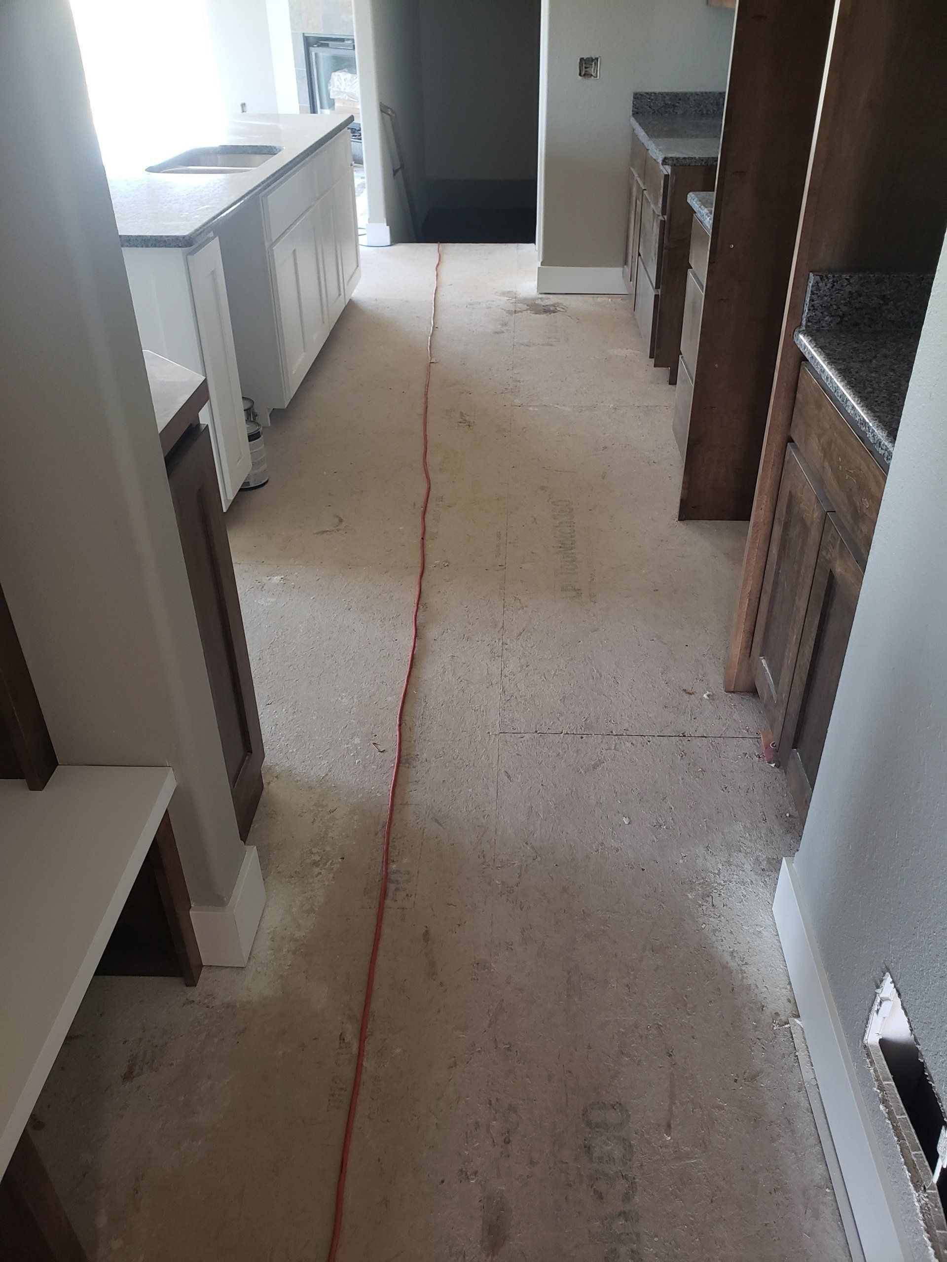 Narrow kitchen hallway with cabinets and appliances on both sides, showing a red line down the center of the floor.