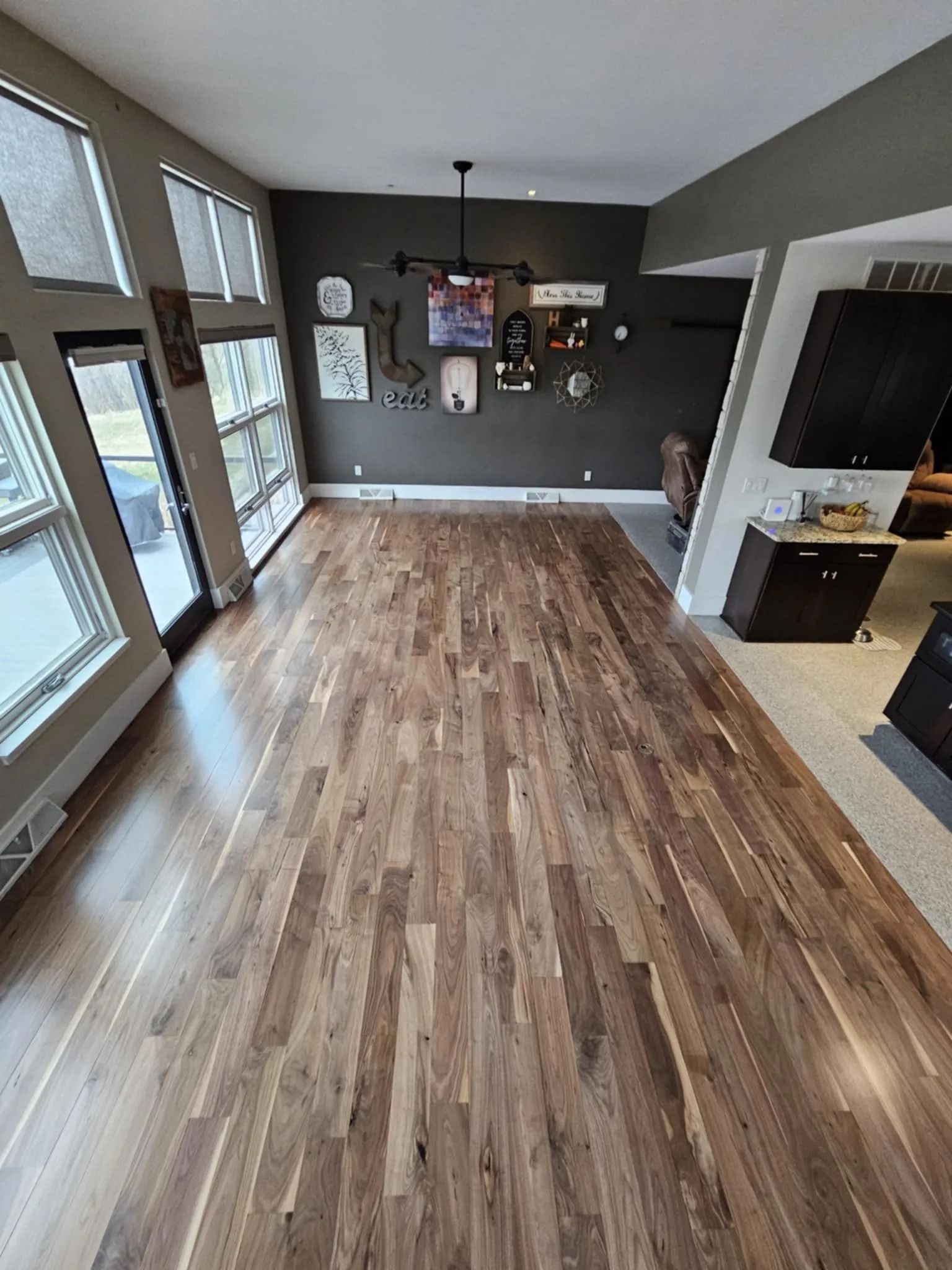 Spacious empty living room with wood floors, gray walls, large windows, and a fireplace nook.