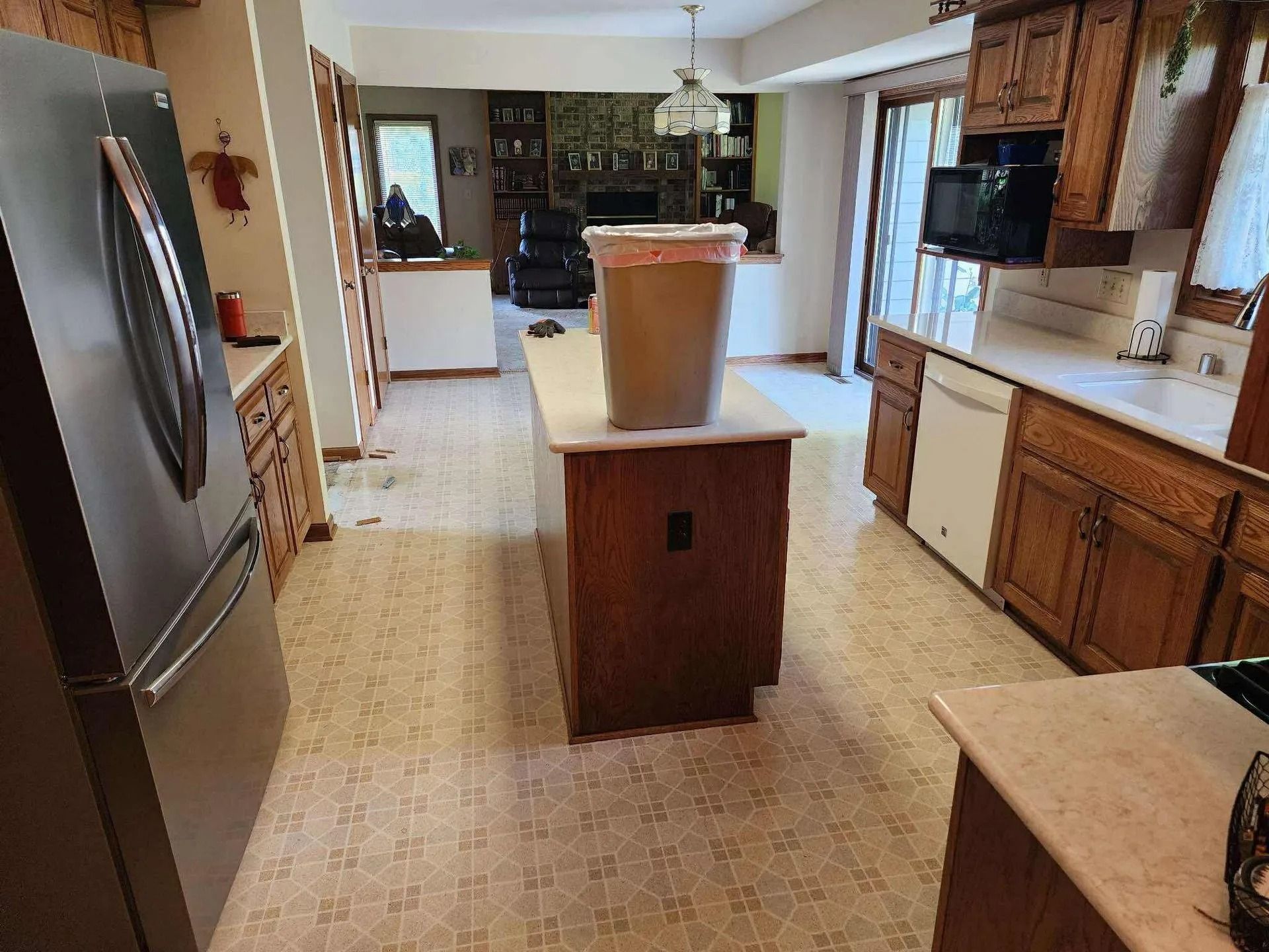Bright kitchen with wooden cabinets, stainless fridge, and island centered in the room