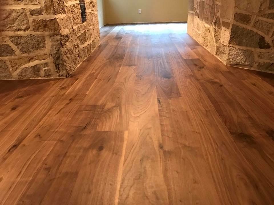 Wooden floor in a stone-walled hallway leading to a bright doorway