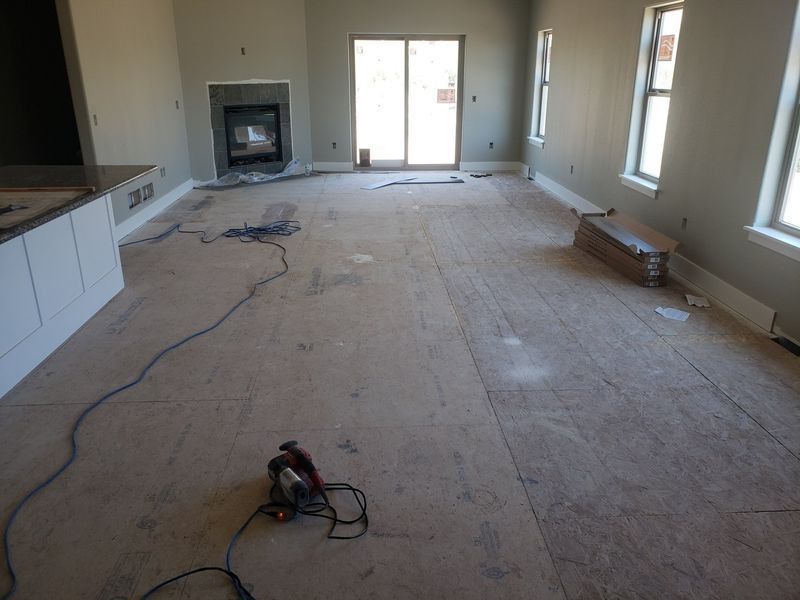 Renovation room with bare subfloor, scattered tools, fireplace, and sliding glass doors.