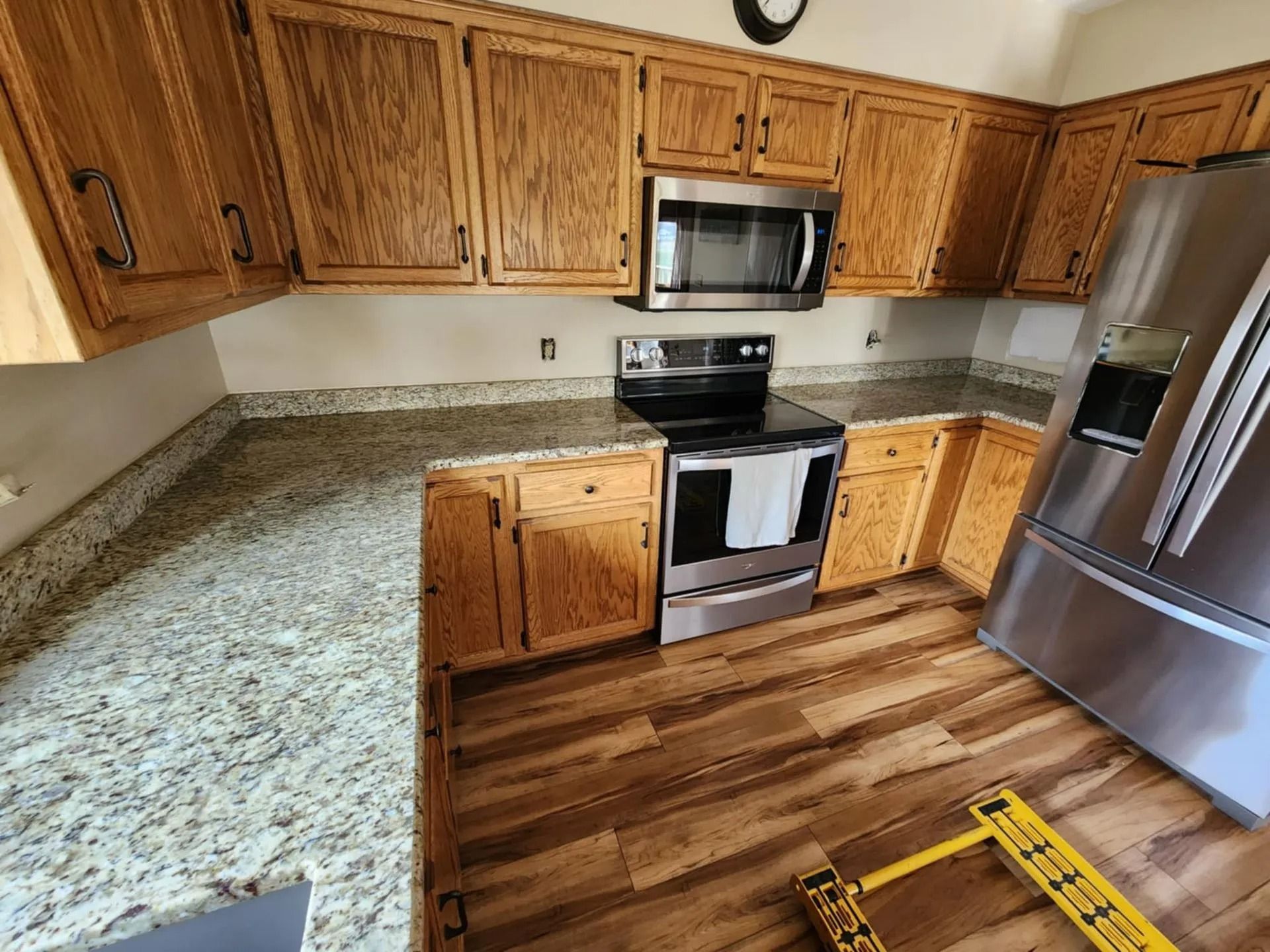 Modern kitchen with wood cabinets, stainless steel appliances, granite counters, and hardwood floor under construction