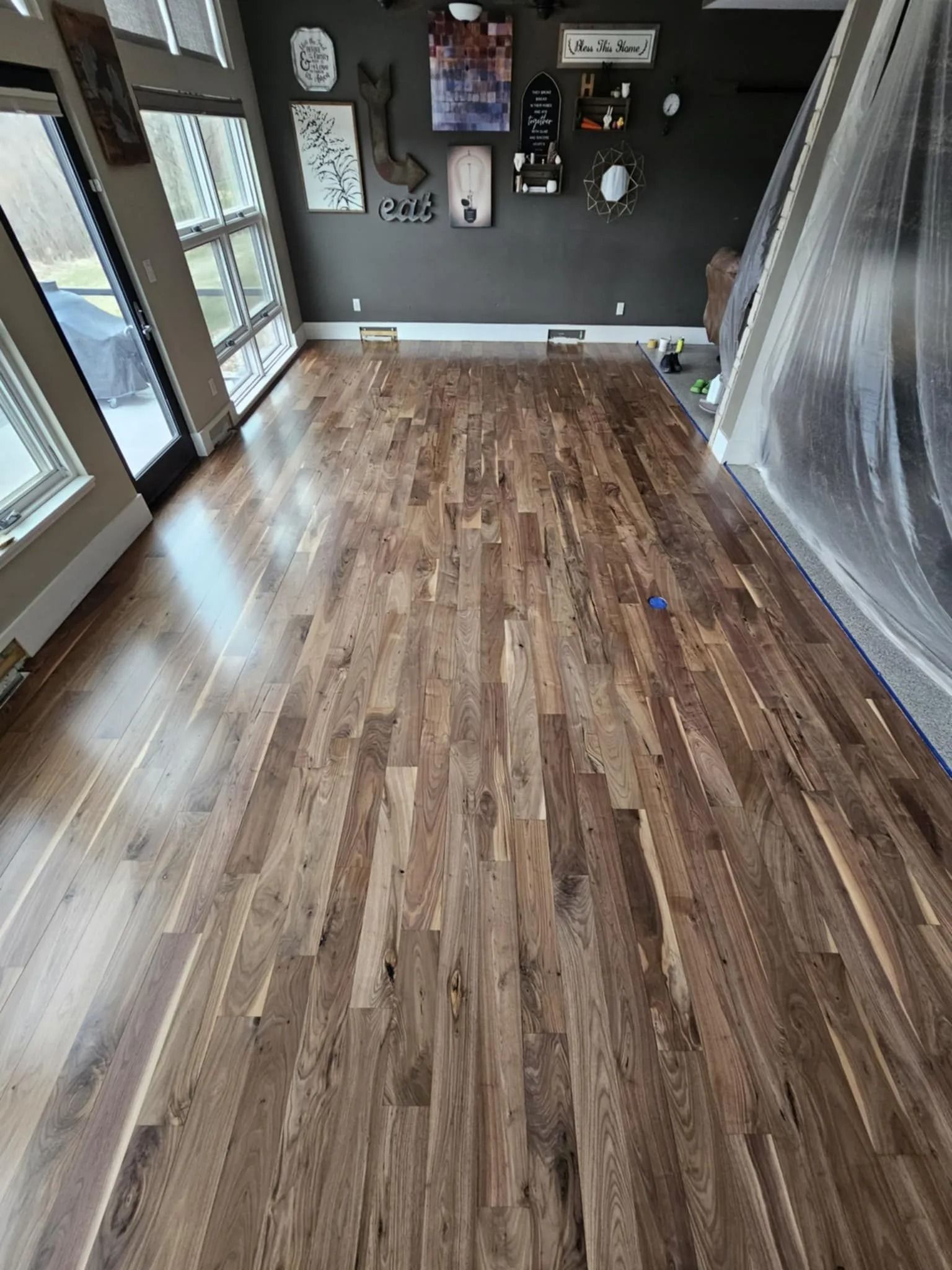 Empty room with wood floors, dark walls, and a plastic-covered area on the right side.
