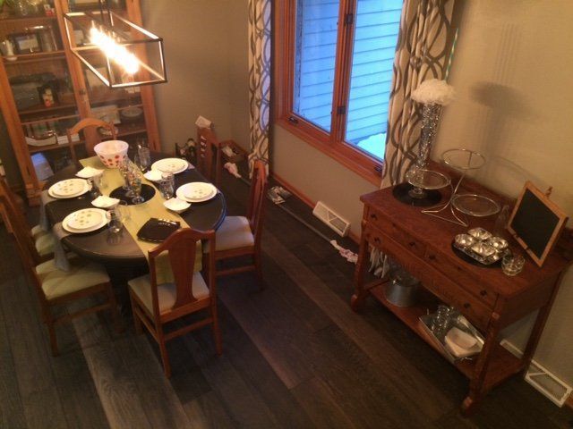 Dining room with a set table, wooden chairs, dark floor, and a sideboard by a window