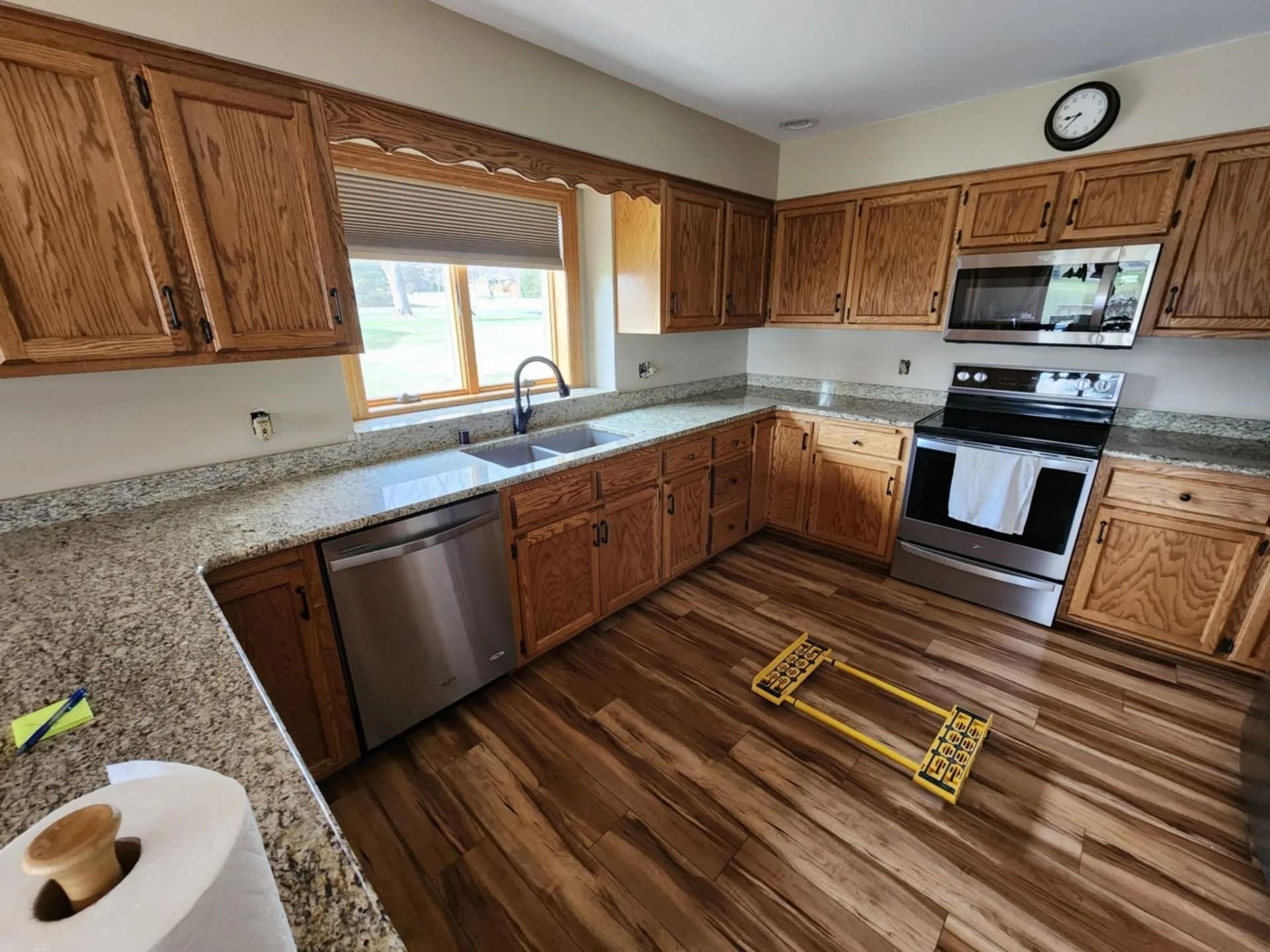 Modern kitchen with wooden cabinets, stainless appliances, and brown wood-look flooring