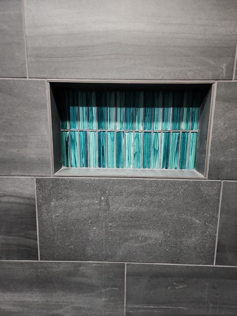 Small window with turquoise curtains set into a gray tiled wall.