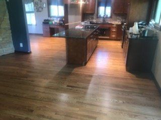 Open kitchen with wooden floors, dark cabinets, and a central island in a warm, modern home.