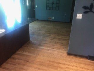 Empty room with wood floors, dark walls, and bright windows on the left.