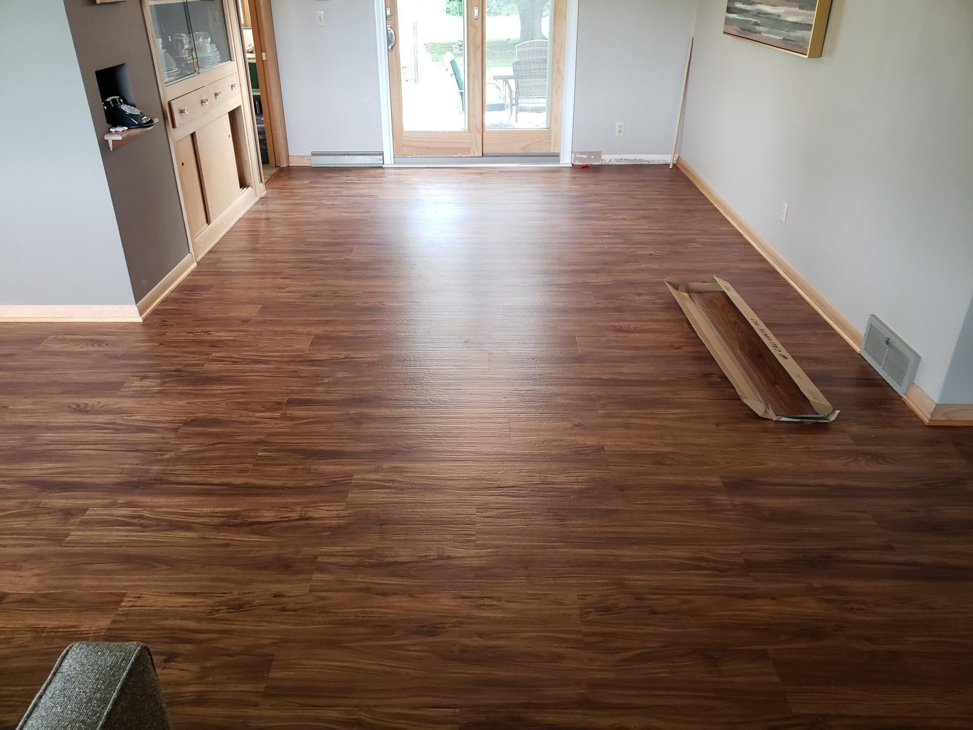 Empty room with wood-look flooring, sliding glass doors, and stacked boards along one wall