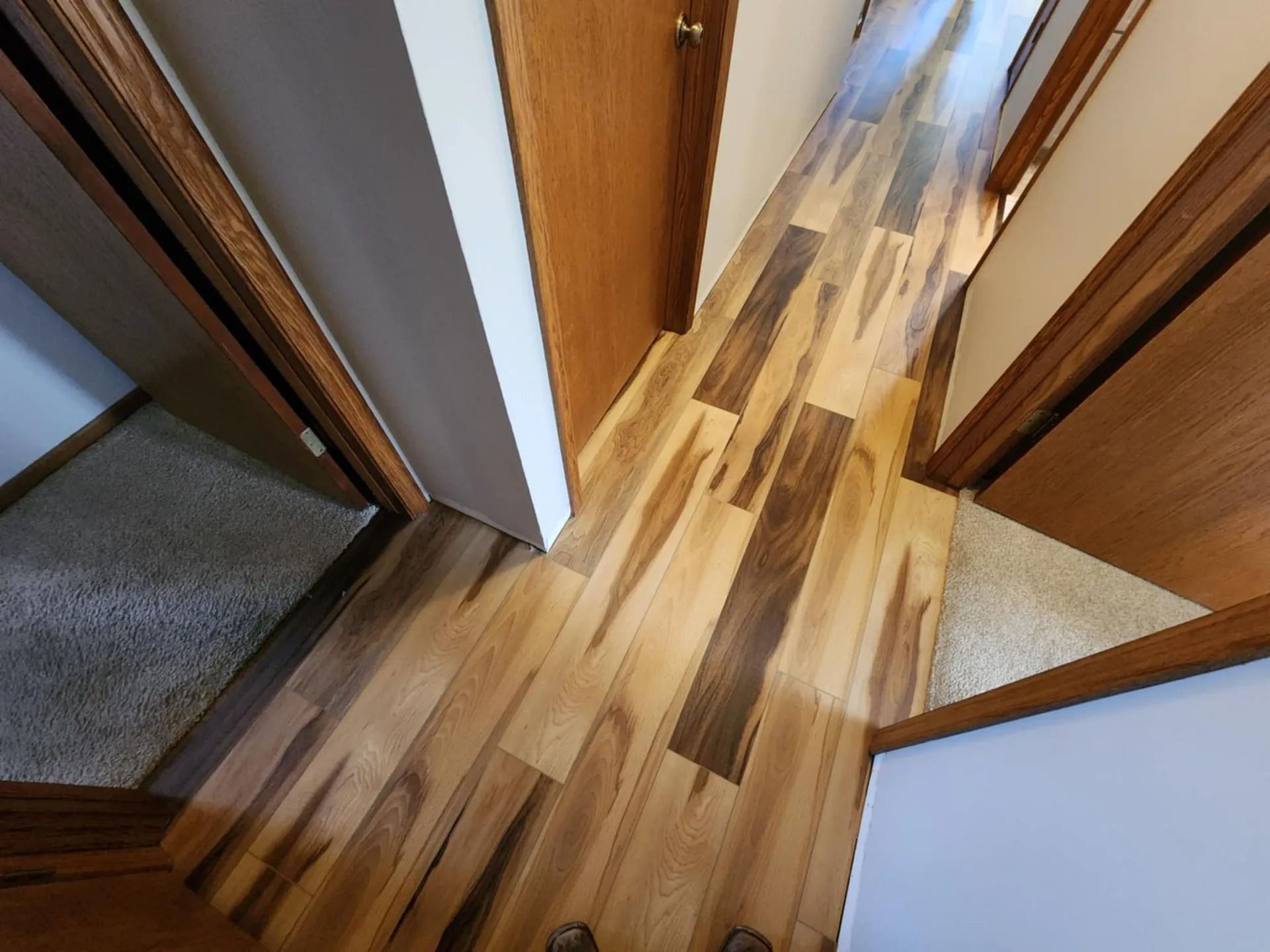 Narrow hallway with wood flooring and wooden doors, viewed from above.