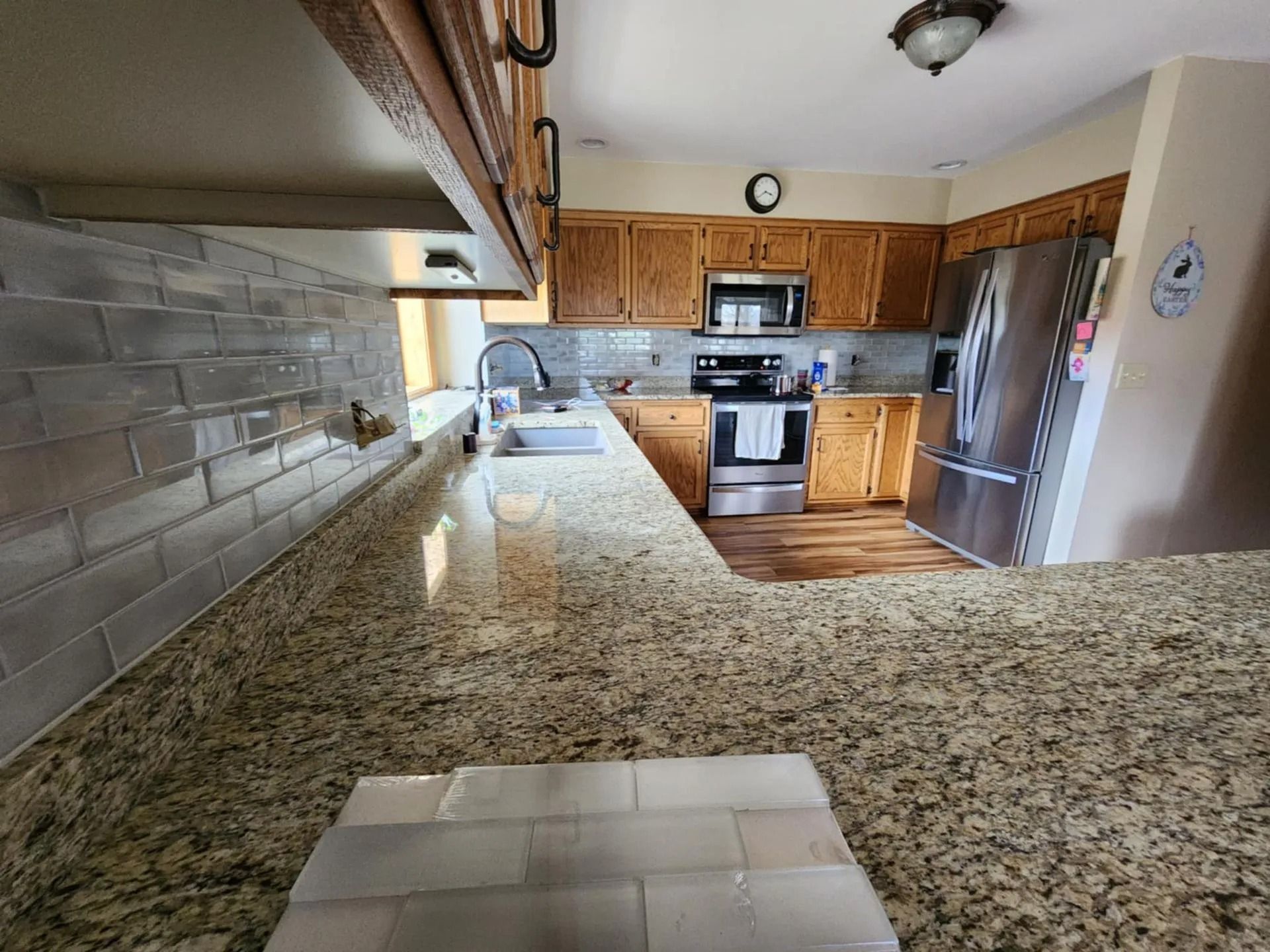 Kitchen interior with granite countertops, wood cabinets, stainless appliances, and tiled backsplash
