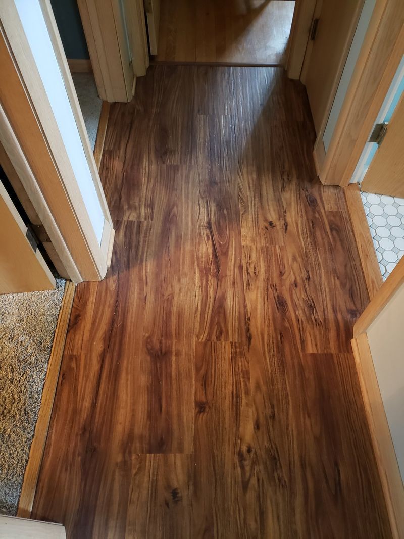 Narrow hallway with wood-look flooring and doorways on both sides