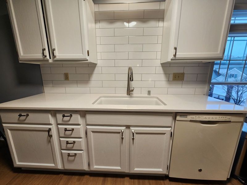 White kitchen with subway tile backsplash, sink, cabinets, and a dishwasher