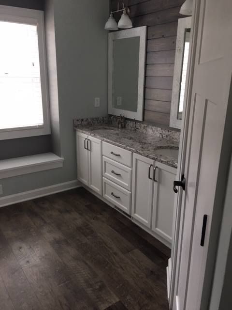 Small bathroom vanity with white cabinets, granite countertop, mirror, and wood-paneled wall