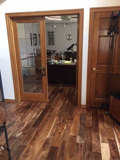Wood-floored office hallway with open glass doors, wood trim, and a desk visible inside