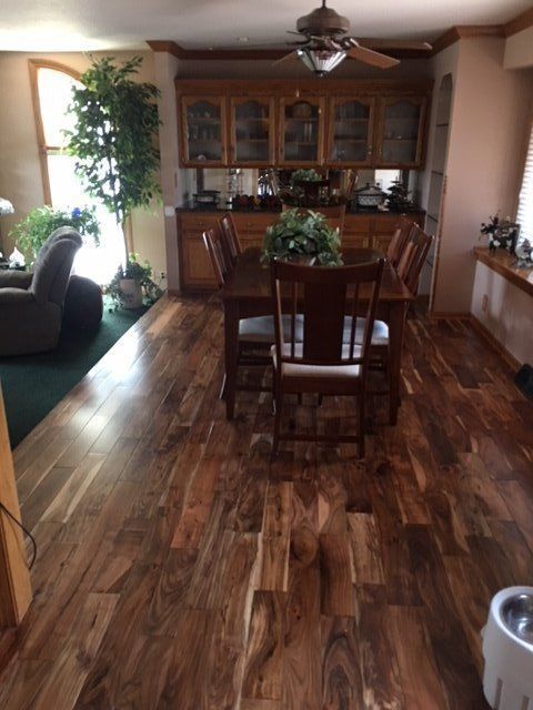 Dining room with wood floors, table and chairs, glass cabinet, and plants in a warm-toned home interior
