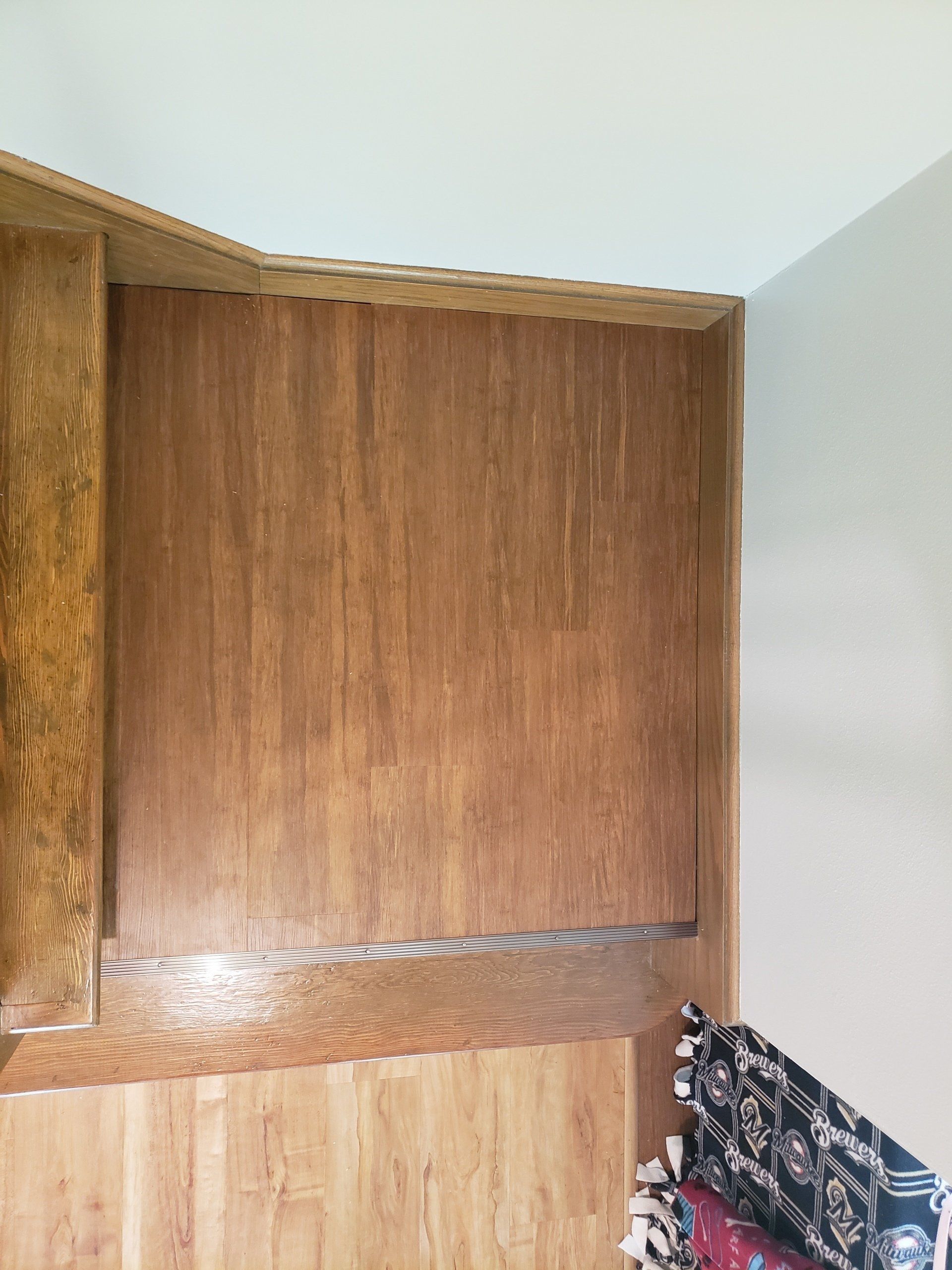 Empty wooden cabinet with a light wood base and a black patterned bag in the lower right corner