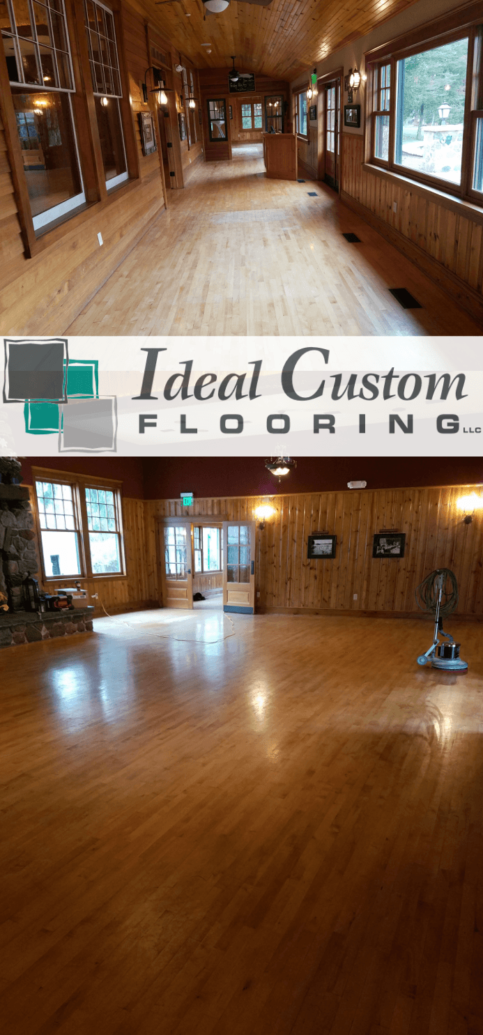 Empty wood-floored room with windows and an “Ideal Custom Flooring” banner across the middle.