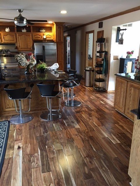 Modern kitchen with wood floors, island seating, stainless fridge, and open shelving