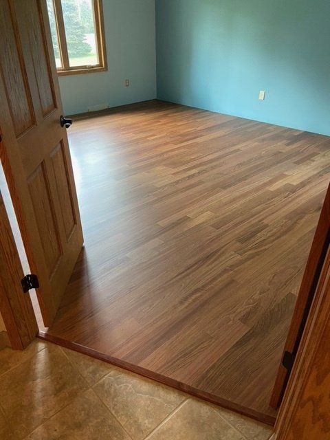 Empty room with blue walls, wood floor, and a window.