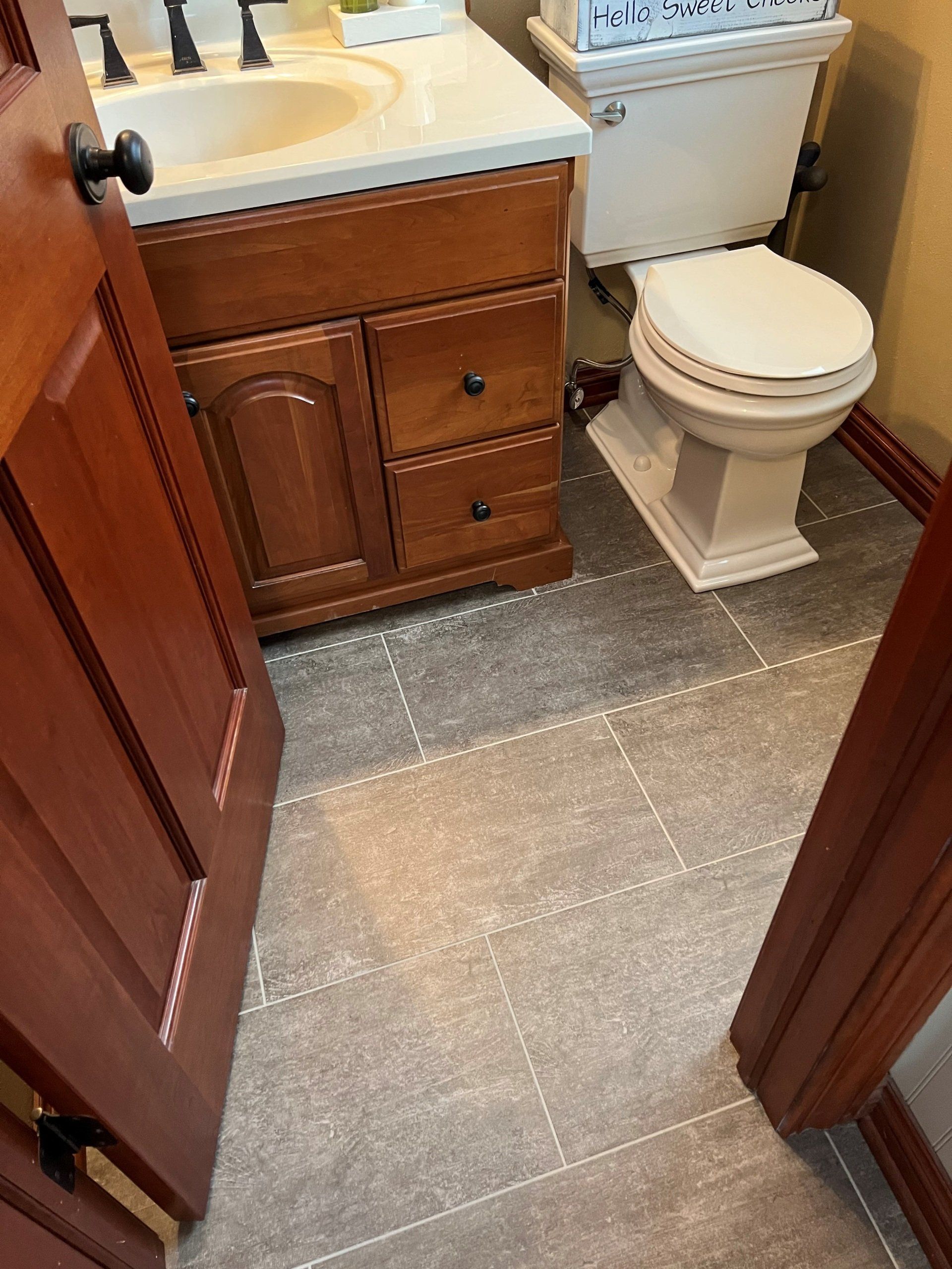 Small bathroom with vanity, sink, toilet, and tiled floor seen through a doorway