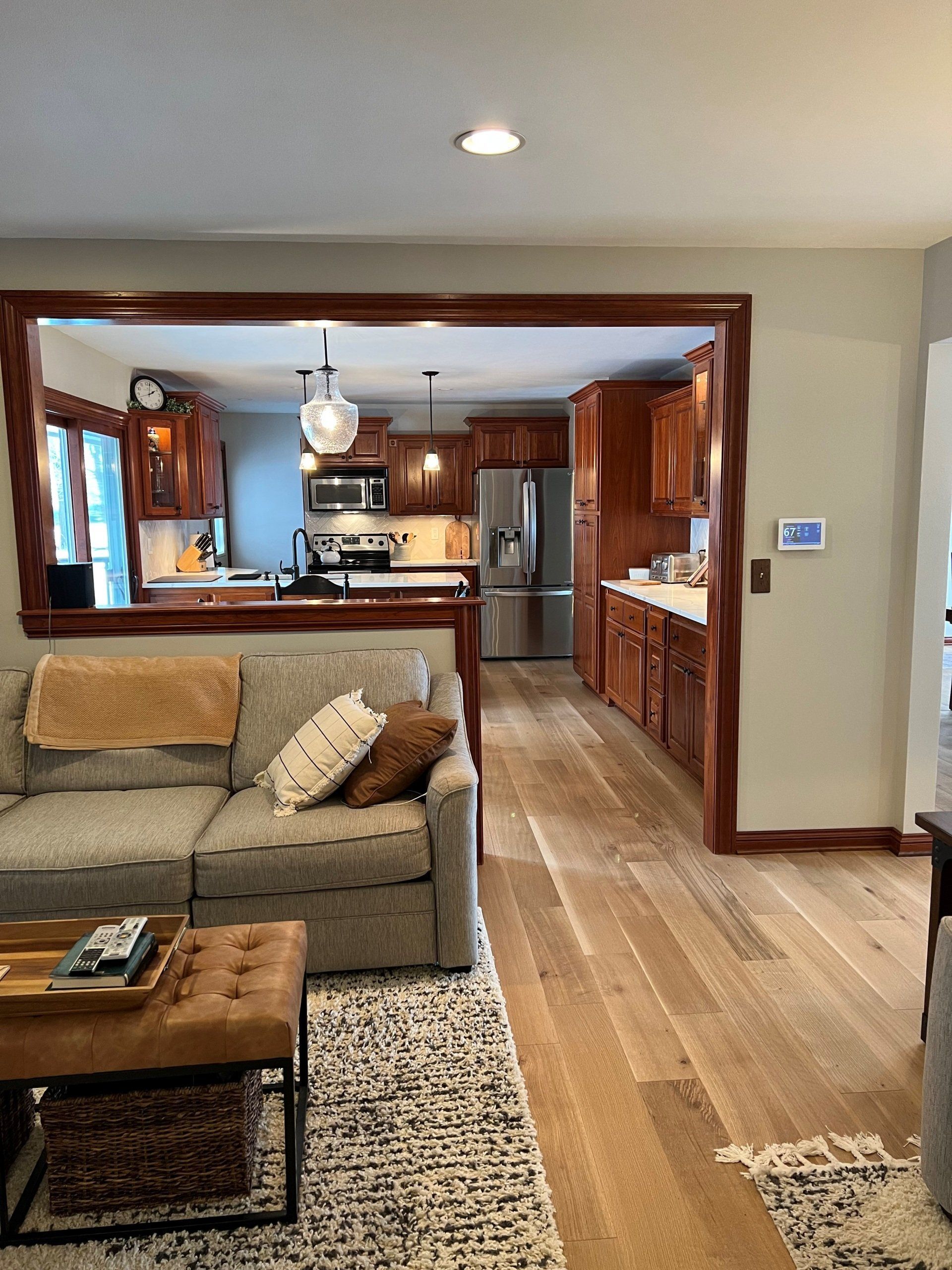 Living room looking into a wood kitchen with hardwood floors and a beige sofa in the foreground