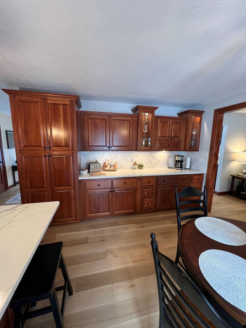 Warm wood kitchen with built-in cabinets, countertop, and dining table in the foreground.