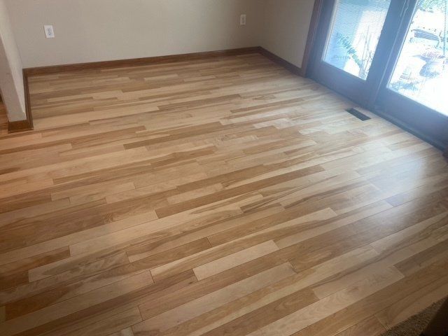 Empty room with light wood flooring and sliding glass doors on the right.