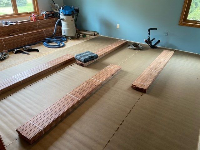Long wooden boards and tools laid out on a room floor under construction